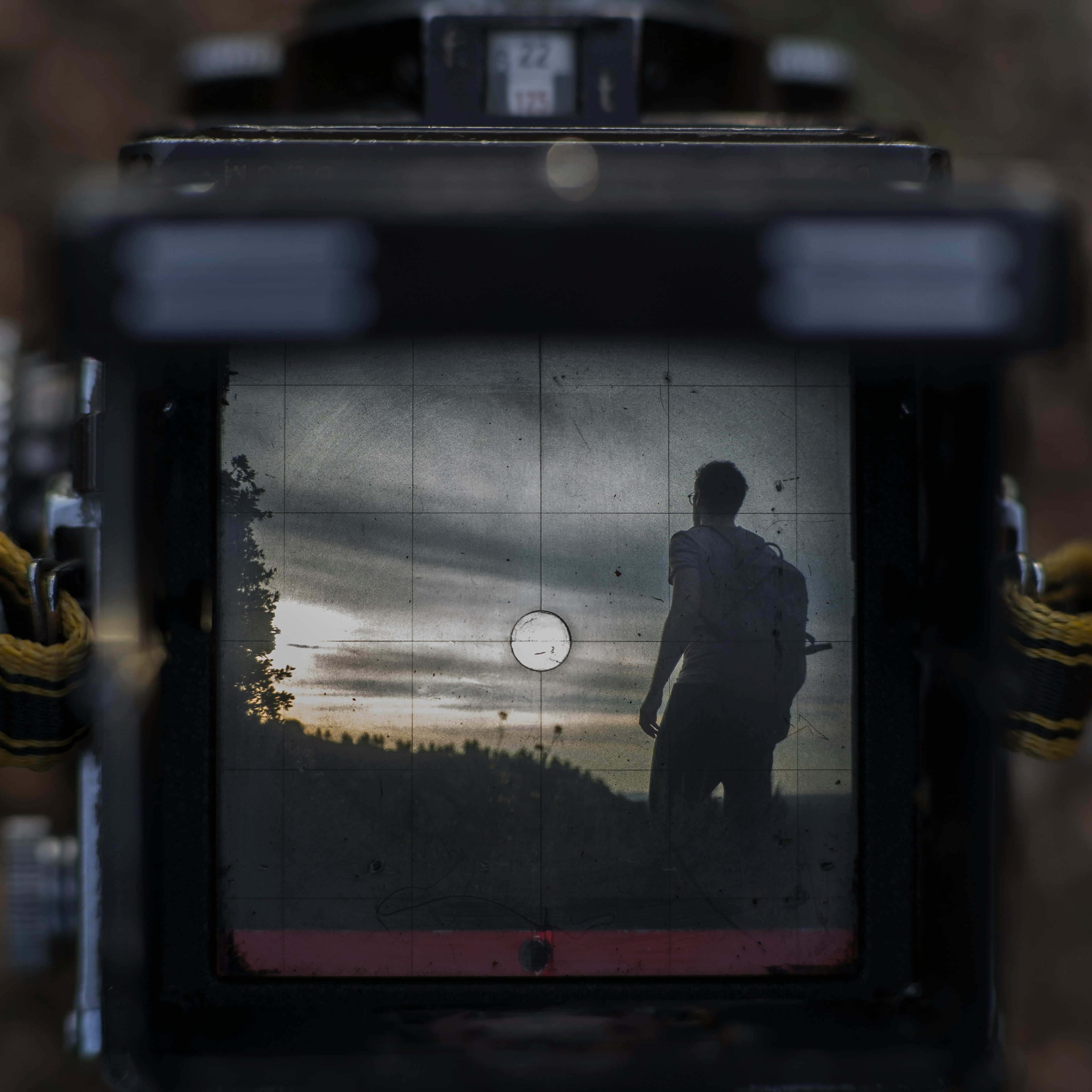 The image shows a camera that is currently filming.  The viewfinder shows a person heading towards a hazy sunset.  Photo by Antonin Duallia on Unsplash.  Find him at https://unsplash.com/@fr0k3.